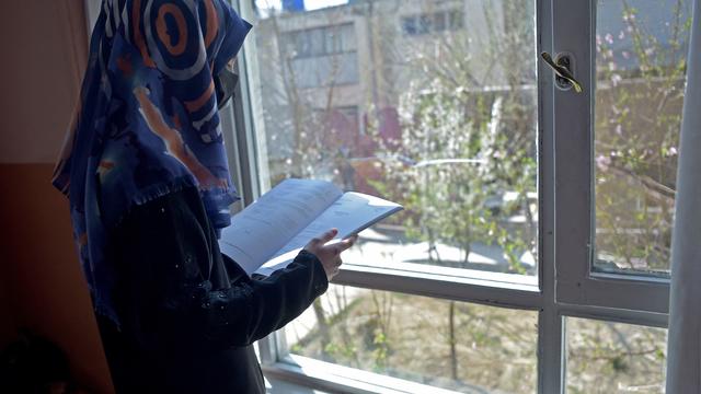 Deena Rahimi, a twelfth-grade student, reads a book at her residence in Kabul on March 21, 2023. Afghanistan's schools reopened in March, but hundreds of thousands of girls remain barred from attending class. 