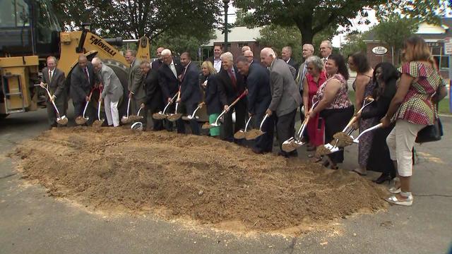 A line of business leaders in Suffolk County each hold a shovel-full of dirt at a groundbreaking ceremony. 
