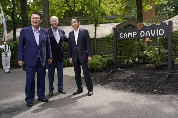 President Biden, center, greets Japanese Prime Minister Fumio Kishida, right, and South Korean President Yoon Suk Yeol, left, during a trilateral summit at Camp David on Friday, Aug. 18, 2023.