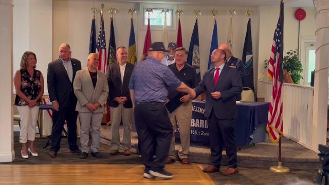 Rep. Andrew Garbarino shakes hands with a Vietnam War veteran as he hands him a commemorative pin. 