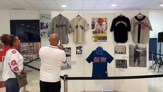 Library visitors take a photo of a display of Negro League baseball jerseys. 