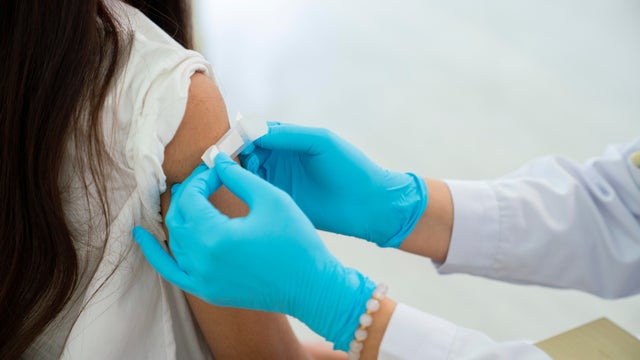 Doctor applies bandage to preteen girl's arm following an immunization 