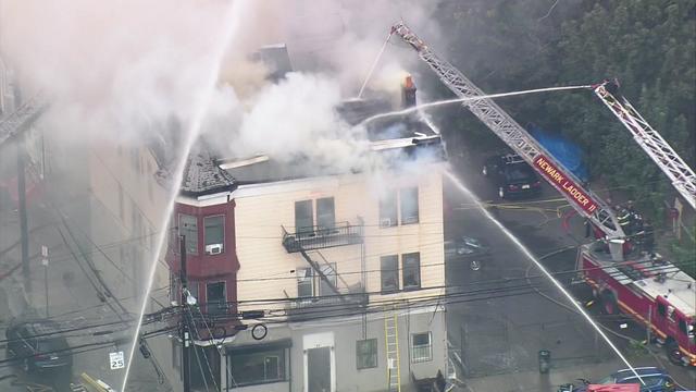 An aerial view of firefighters battling a fire at a three-story apartment building. 