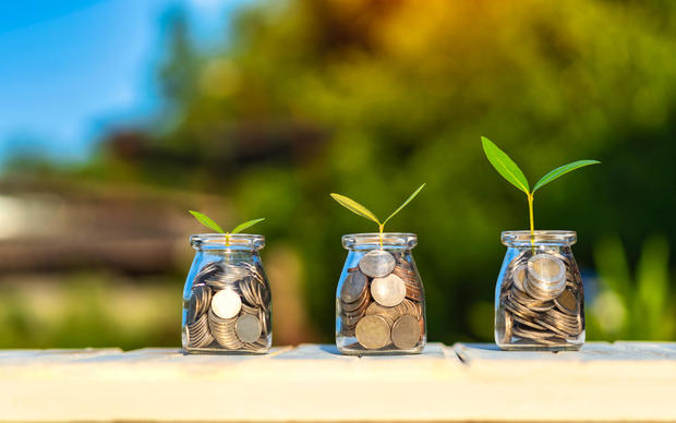 Savings and investment concept. Young plant growing in the glass jars that have money. Coins and plants are grown on a pile of coins for finance and banking. 