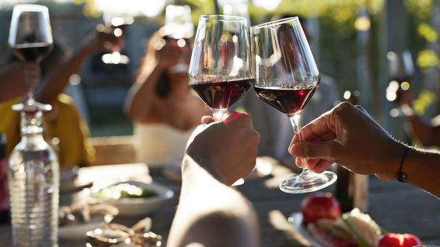 Friends toasting glasses with red wine in wedding 