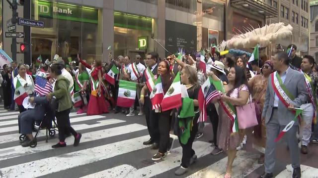 Crowds carry Mexican flags and wear sashes with the colors of the Mexican flag as they march in the Mexican Day Parade. 