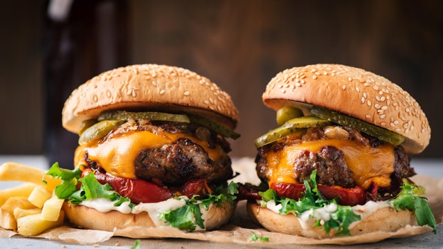 Two juicy craft cheeseburgers with roasted bell pepper and pickles 