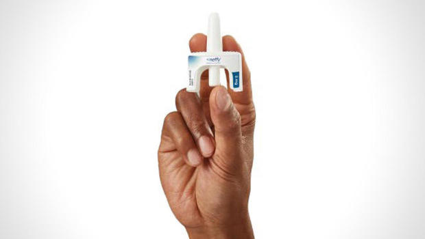 A person's hand holding a vial of Neffy epinephrine nasal spray 