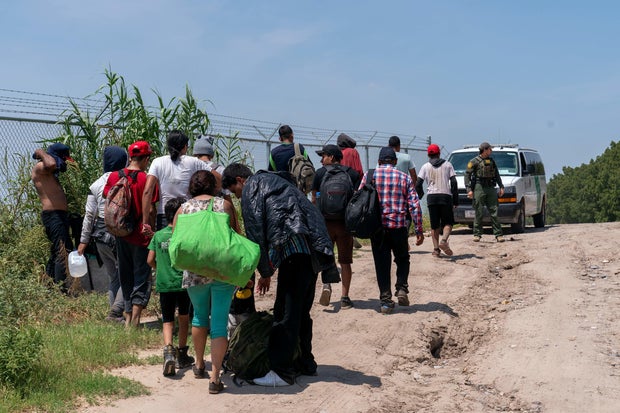 A group of migrants who have crossed into the U.S. from Mexico in Eagle Pass, Texas, are led by a Border Patrol Agent on Aug. 25, 2023.