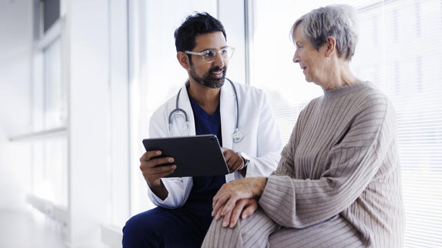 Doctor and patient in conversation, looking at digital tablet 