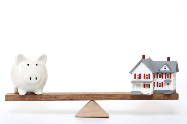 Model house and piggy bank on seesaw - Concept of Investment in real estate 