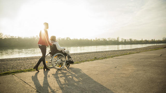 Adult granddaughter assisting her grandmother sitting in wheelchair 