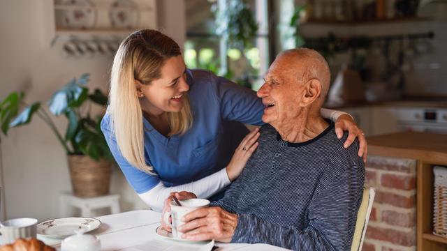 Caregiver or healthcare worker visiting senior man at home. 