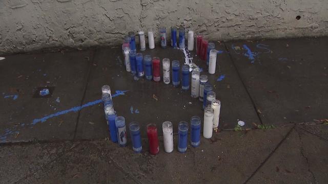 Blue, red and white candles sit in the shape of an S outside an apartment building. 