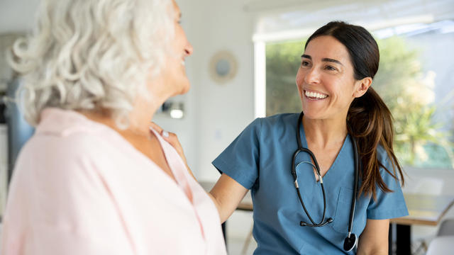 Happy doctor talking to a senior woman on a house call 