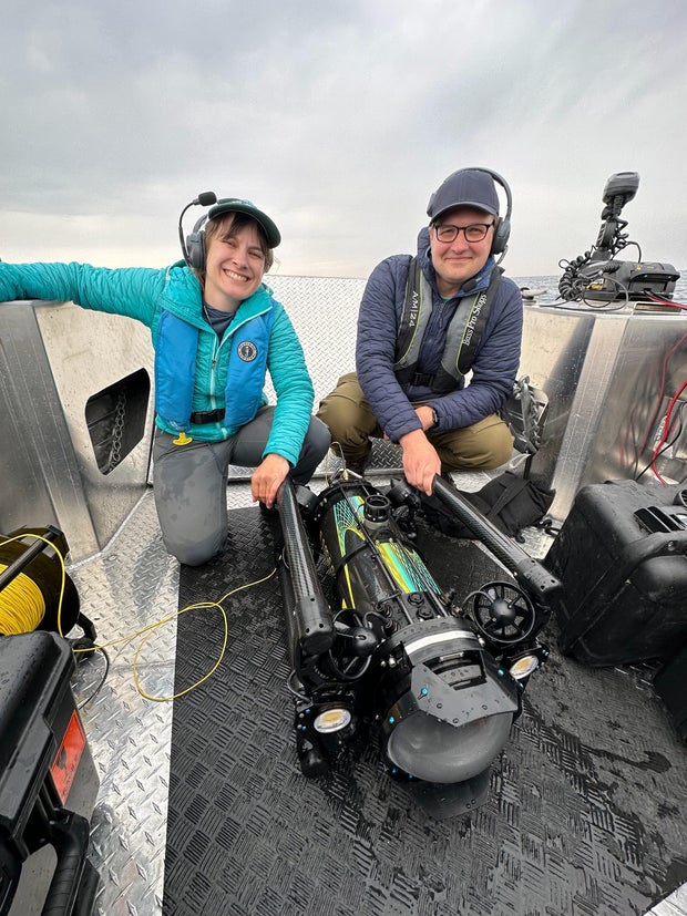 Yvonne Drebert (left), and Zach Melnick (right), moments after the discovery of the Africa, with their robot, Kiyi (center)
