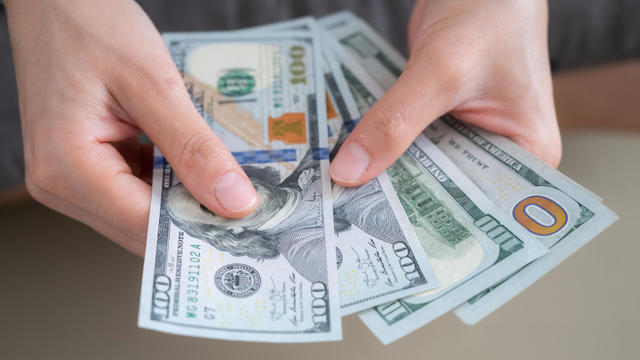 Close up of someone hands holding and counting American dollar banknotes in her hand. 