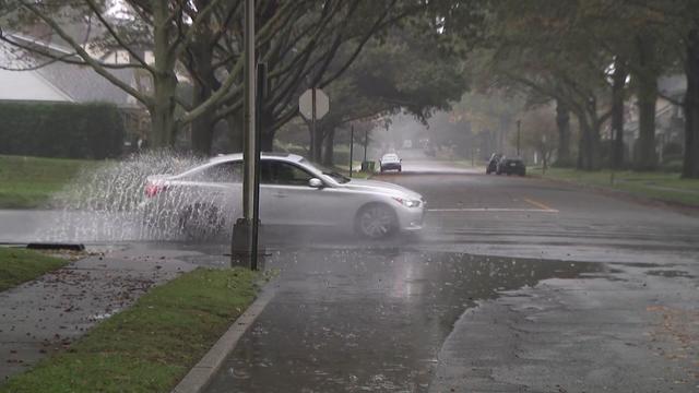 A vehicle splashes up water as it drives through a large puddle on a street corner in Hempstead. 
