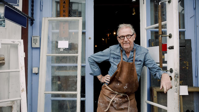 Portrait of senior hardware store owner standing with hand on hip while leaning on door 