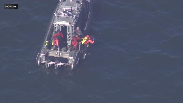 Water rescue crews jump off a boat into the water in the Long Island Sound. 