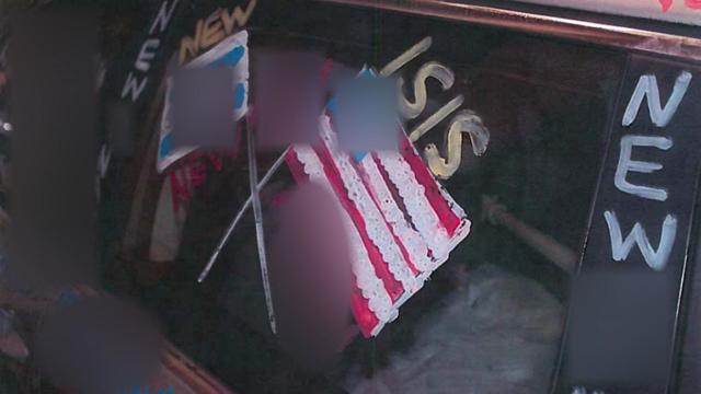 Graffiti on a vehicle's window depicting United States and Israeli flags with swastikas on them and the words "New ISIS." 