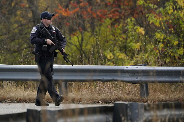 A police officer walks along a rural road during a manhunt for the Maine mass shooting suspect, Oct. 26, 2023, in Lisbon, Maine. 