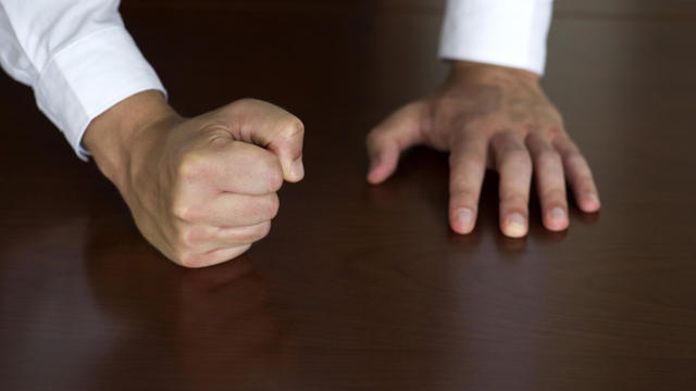 Businessman pounding fist on table, cropped 