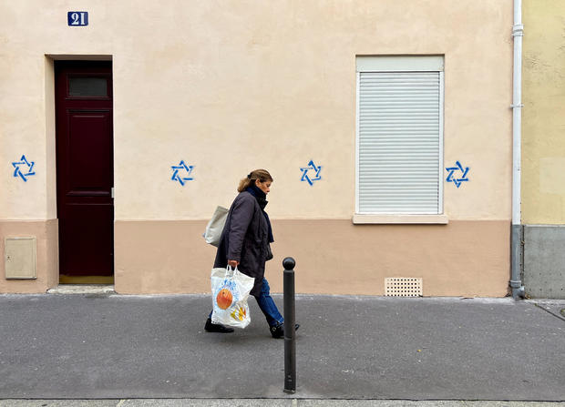 A woman walks past a building tagged with Stars of David in Paris, France, Oct. 31, 2023. 