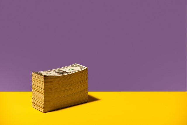 Stack of US $1 bills sitting on yellow background 