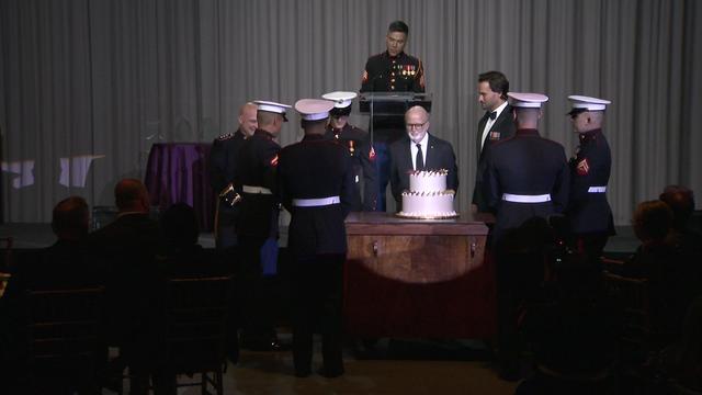Marines and other officials stand around a birthday cake. 