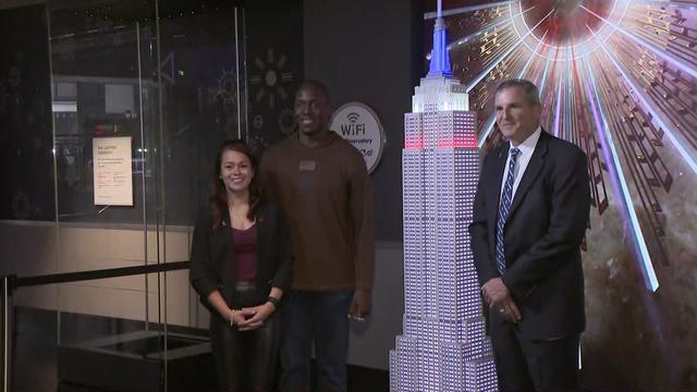 Kevin Boothe, Antoinette Wallace and Mike Linnington stand next to a lit scale model of the Empire State Building. 