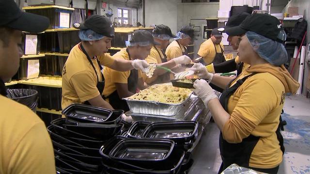 Workers pack food into takeout packages. 