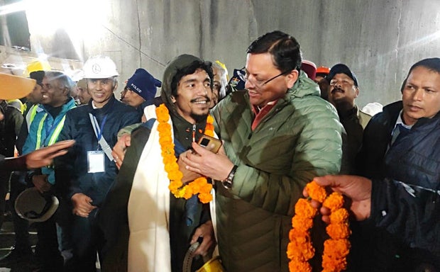 Uttarakhand Chief Minister Pushkar Singh Dhami, center right, greets a worker rescued from a partially collapsed tunnel in Uttarkashi, India, Nov. 28, 2023.