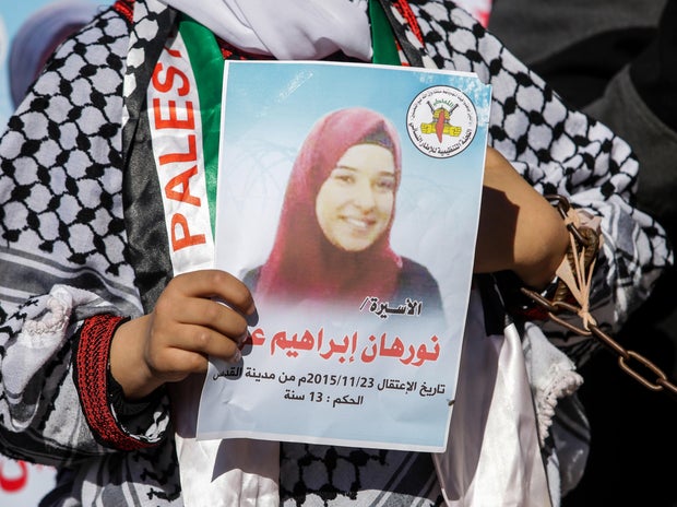 A Palestinian woman holds a poster of a prisoner Nourhan