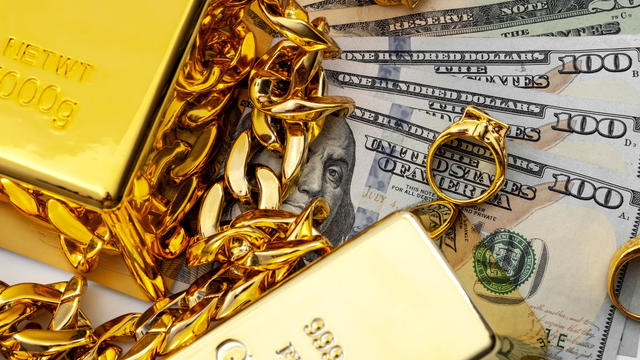 Jewelry buyer, pawn shop and buy and sell precious metals concept theme with a pile of cash in US dollars, golden rings, necklace bracelet and gold bullion isolated on white background 