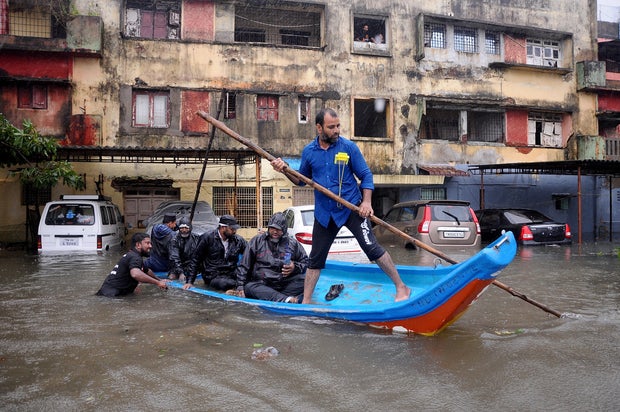 People move in a boat past partially submerged vehicles in a residential area following heavy rains ahead of Cyclone Michaung in Chennai, India