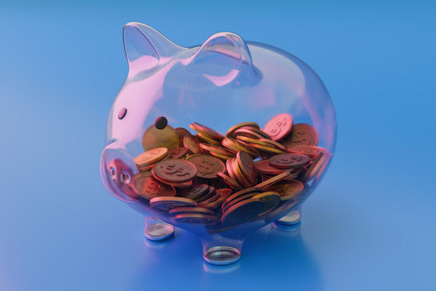 See Through Transparent Glass Piggy Bank With Coins on Blue Background 