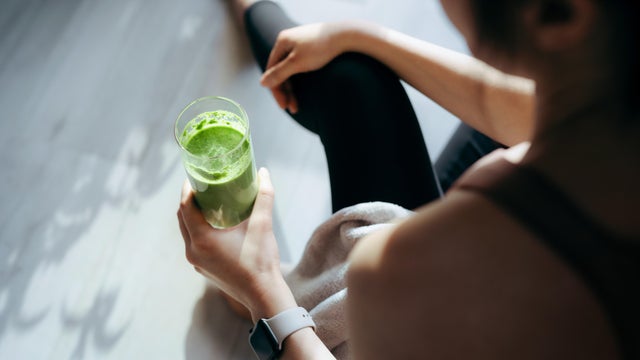Over the shoulder view of woman taking a break, refreshing with green juice