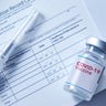 Covid-19 vaccination record card with a vial of a Covid-19 booster dose 