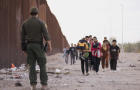 A Customs and Border Protection officer near migrants at the U.S.-Mexico border in Lukeville, Arizona, on Monday, Dec. 11, 2023. 