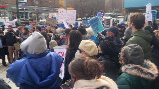 Dozens of people gathered in a crowd outside Mount Sinai Beth Israel, some holding protest signs. 