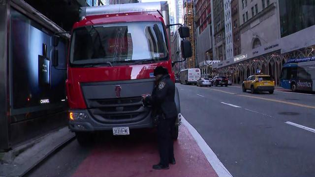 An NYPD traffic agent writes a ticket for a vehicle parked in a bus lane. 