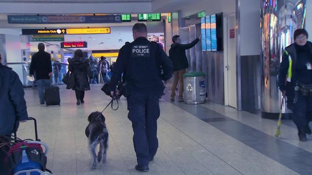 A Port Authority Police officer walks through an airport with a dog on a leash. 