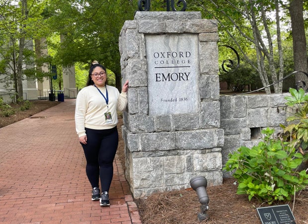 Ashley Rodriguez standing by a sign for Oxford College of Emory University