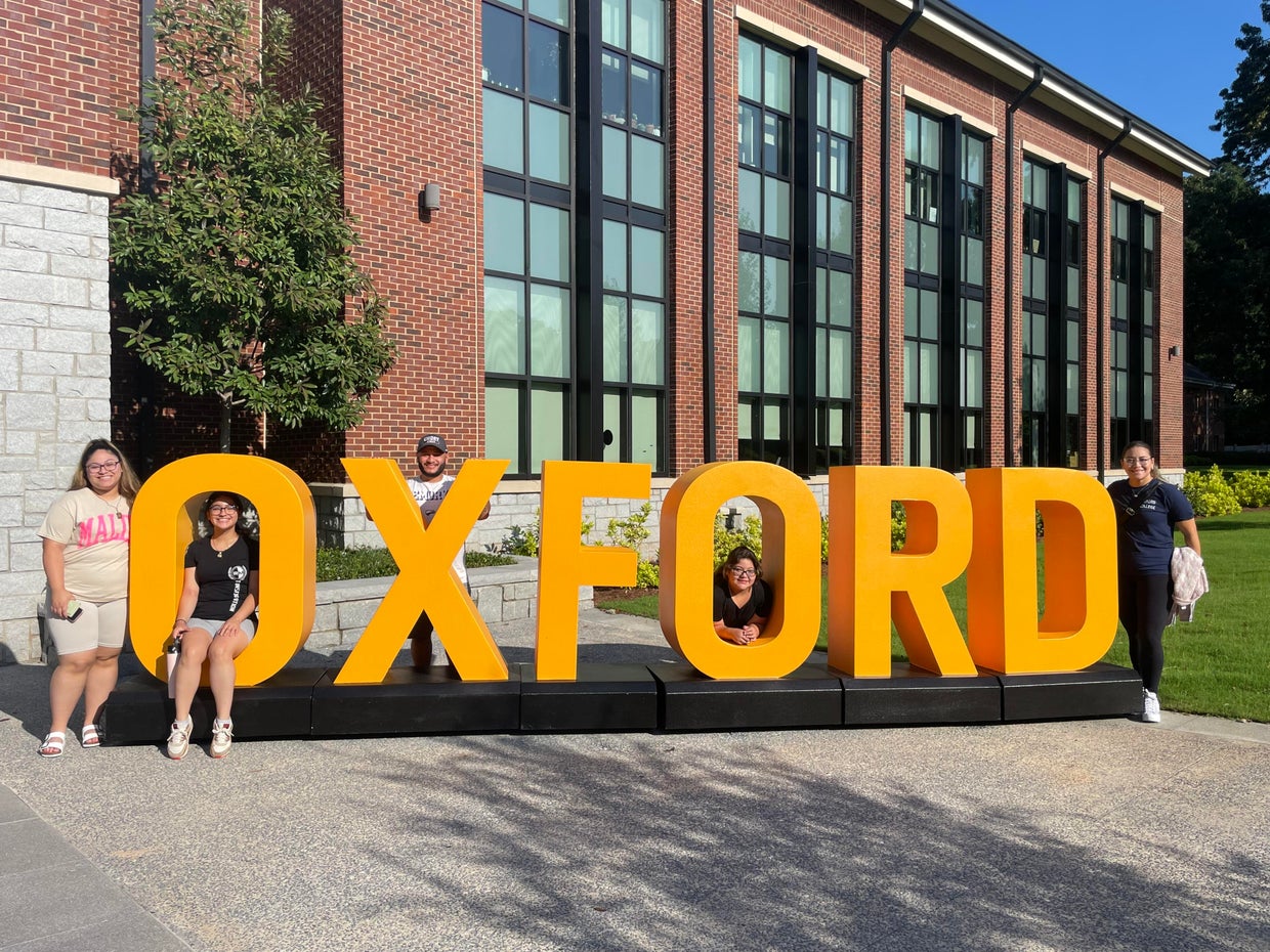 Rodriguez family standing by a sign for Oxford College 