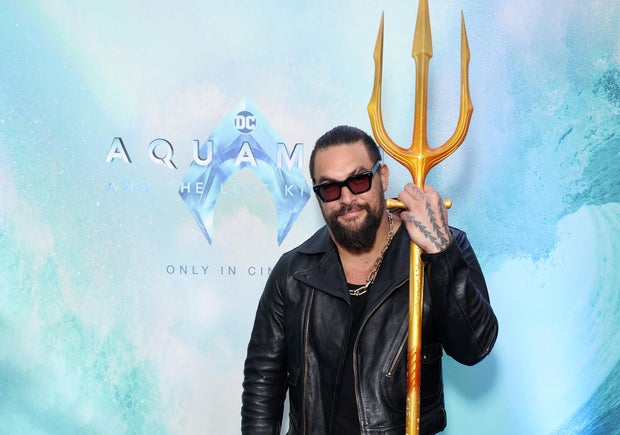Actor Jason Momoa holds a trident at an event for his new film,