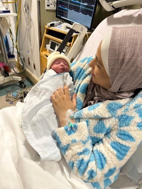 Fatima Alshawabkeh sits in a hospital bed holding her newborn son.