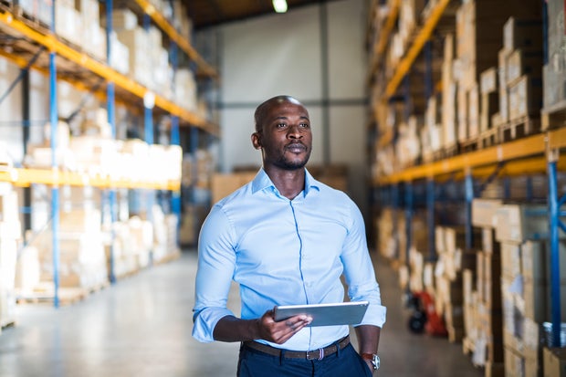Mature man manager in blue shirt with tablet in a warehouse.