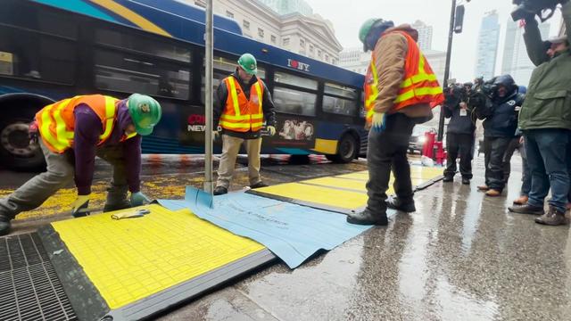 MTA crews put yellow trench covers on top of subway grates in New York City sidewalks. 