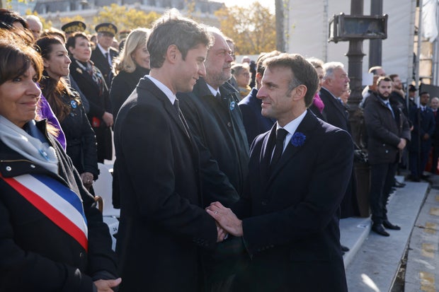 French President Emmanuel Macron (R) shakes hands with then Education and Youth Minister Gabriel Attal (L) during a ceremony at the Tomb of the Unknown Soldier at the Arc de Triomphe in Paris, Nov. 11, 2023